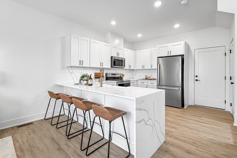 A kitchen with white cabinets and a marble island.