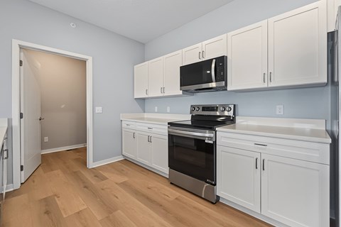A kitchen with white cabinets and a black microwave.