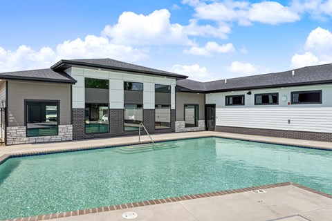 A swimming pool in front of a building with a clear blue sky.