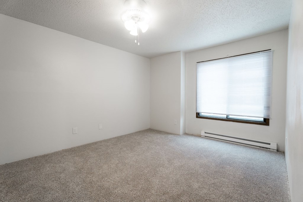 A room with a carpeted floor, a window with blinds, and a ceiling light. at Bristol Ridge, Urbandale, IA, 50322