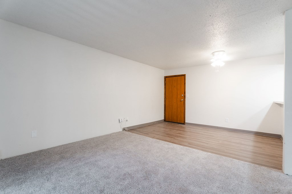 A room with a carpeted floor and a wooden door. at Bristol Ridge, Urbandale, IA, 50322