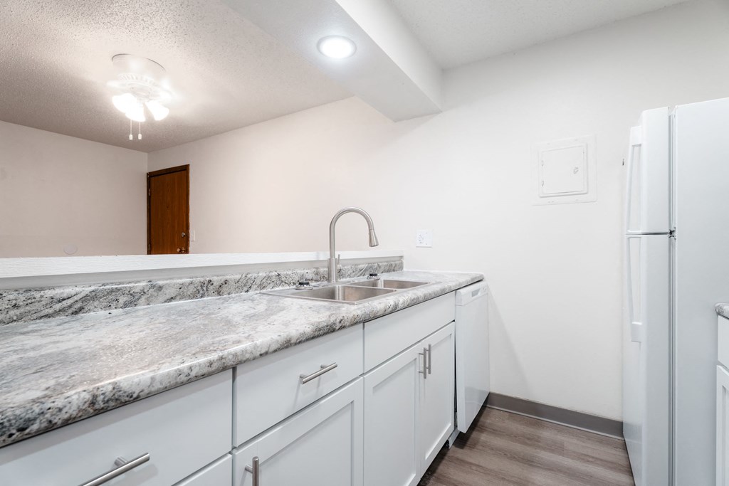 A kitchen with a marble countertop and white cabinets. at Bristol Ridge, Urbandale, IA