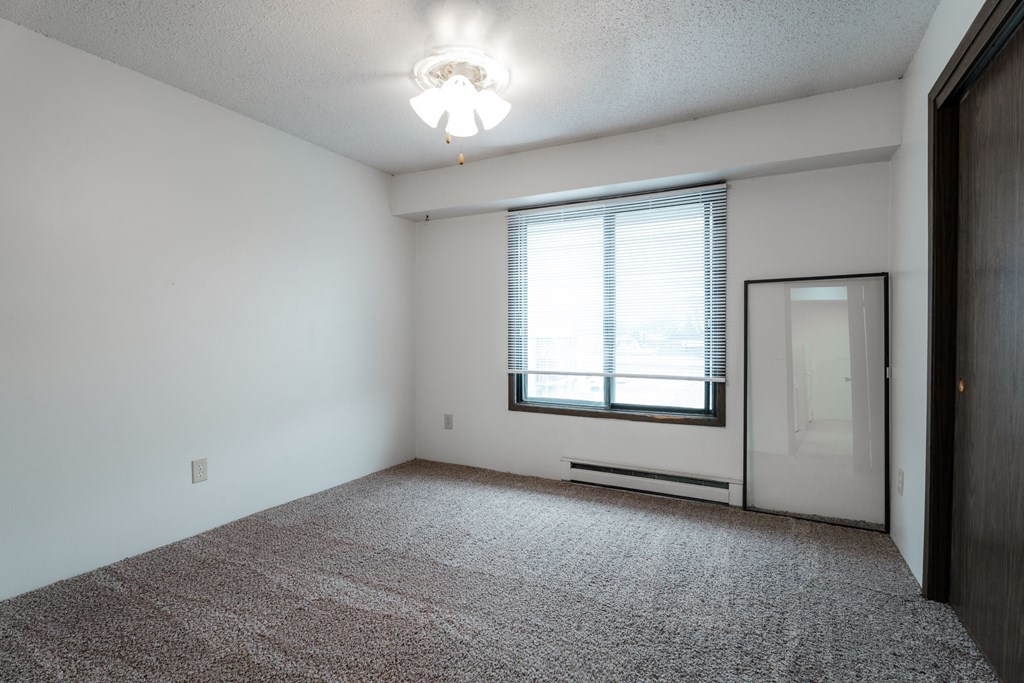 A room with a carpeted floor and a window with blinds. at Bristol Ridge, Urbandale, IA