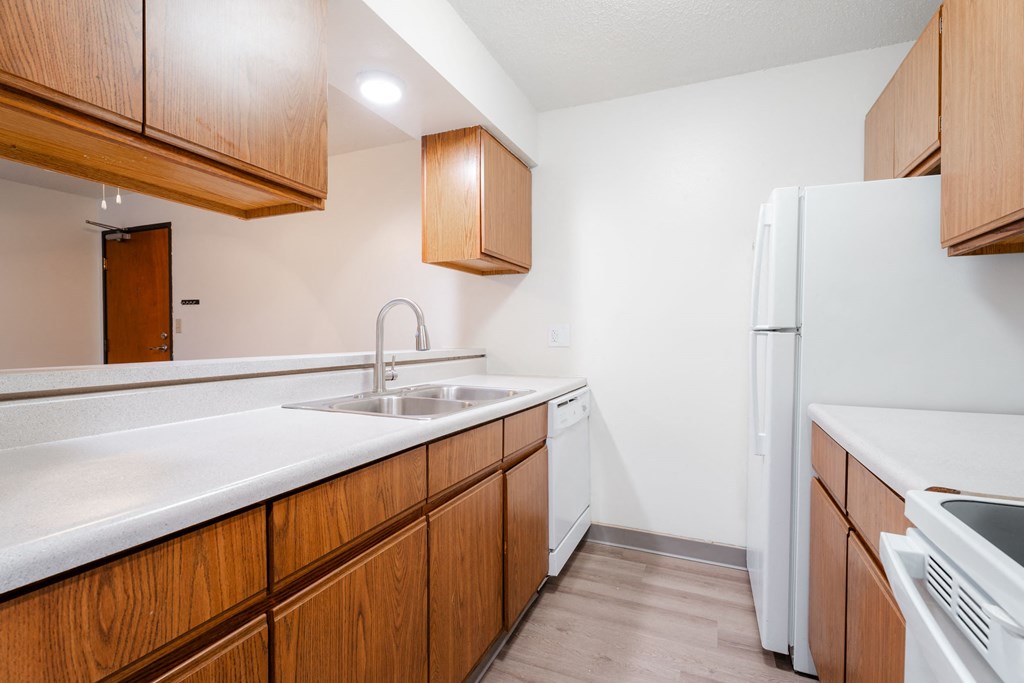 A kitchen with wooden cabinets and a white fridge. at Bristol Ridge, Urbandale, 50322