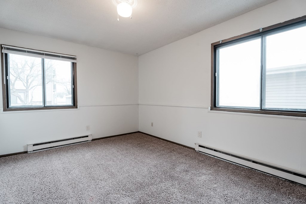 A room with a carpeted floor and two windows. at Bristol Ridge, Urbandale