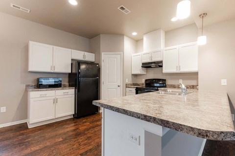 A kitchen with a black refrigerator and white cabinets.