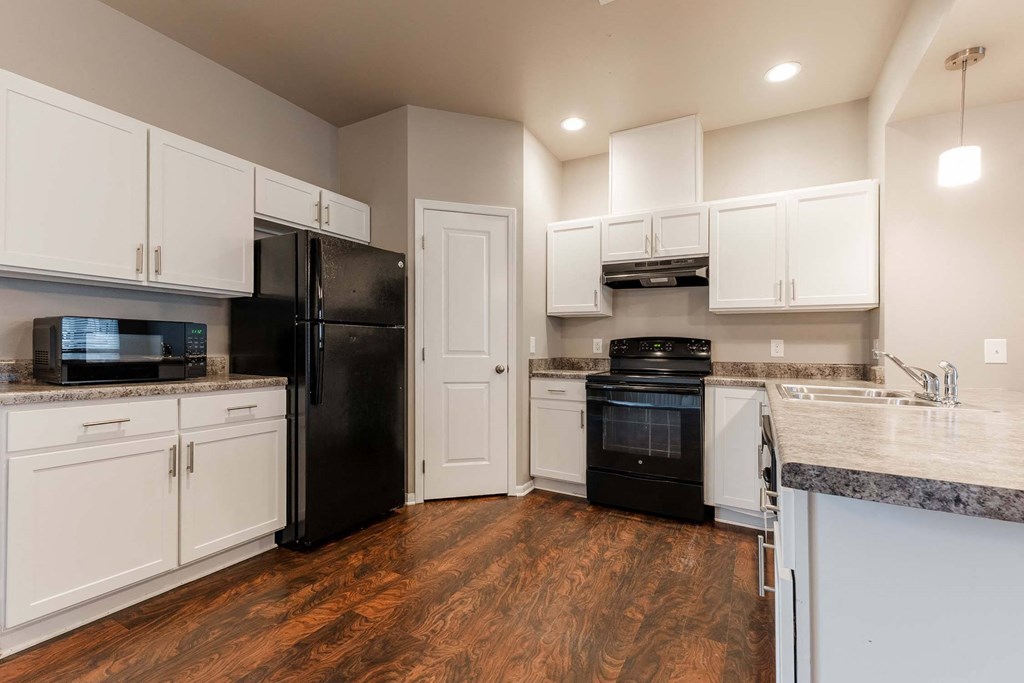 A kitchen with black appliances and white cabinets. at Danamere Village, Carlisle, Iowa