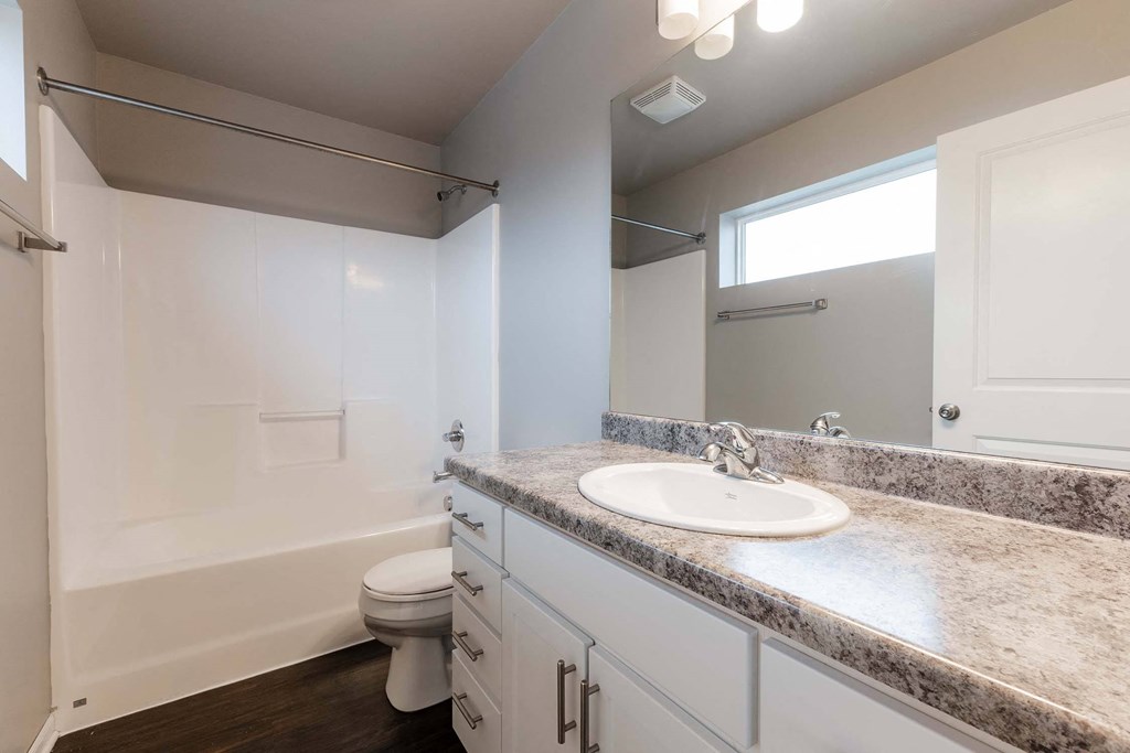 A bathroom with a toilet, sink, and a window. at Danamere Village, Carlisle, IA