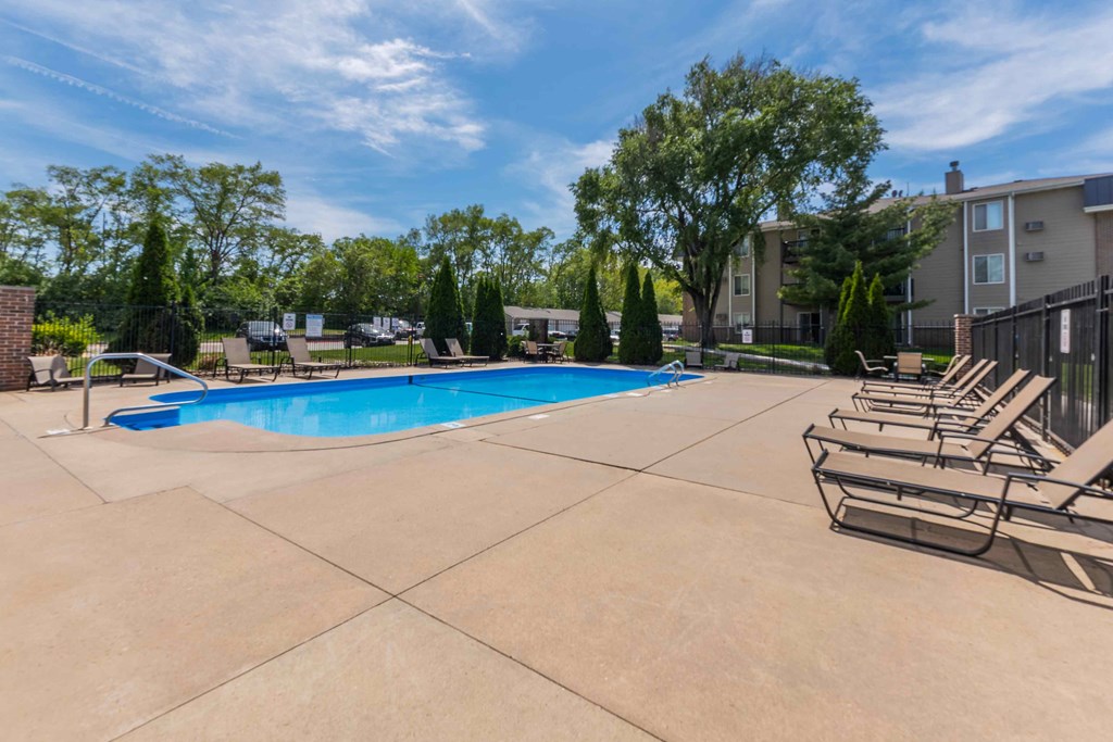 A swimming pool surrounded by lounge chairs and trees.