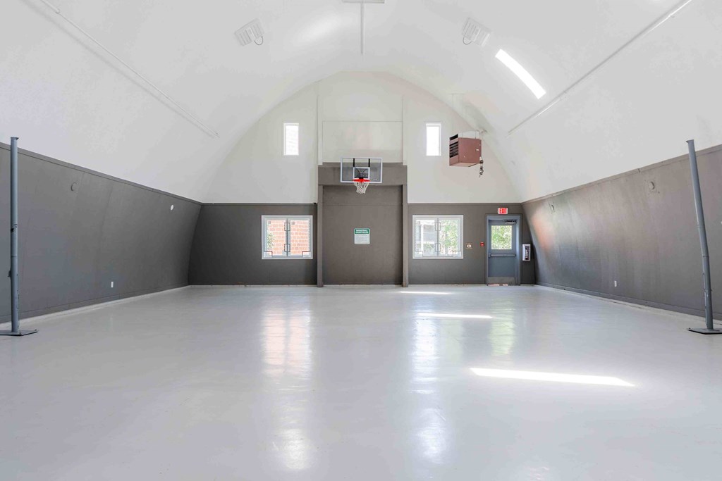 A spacious indoor basketball court with a white floor and walls.