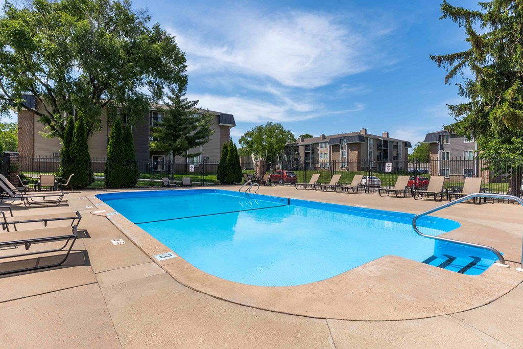 A swimming pool surrounded by lounge chairs and trees.