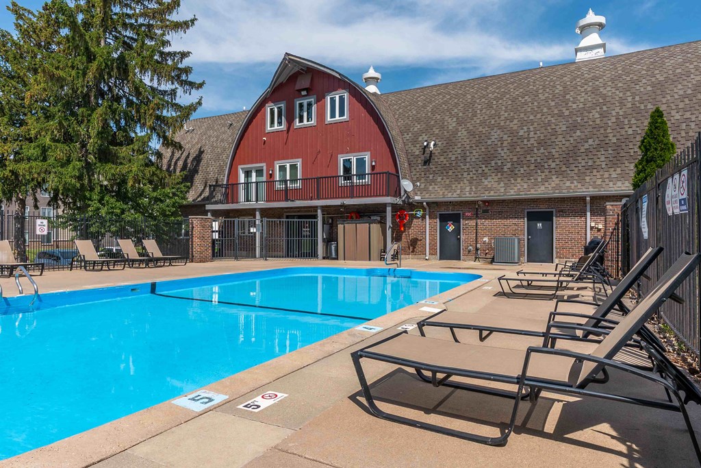 A large swimming pool in front of a red barn.