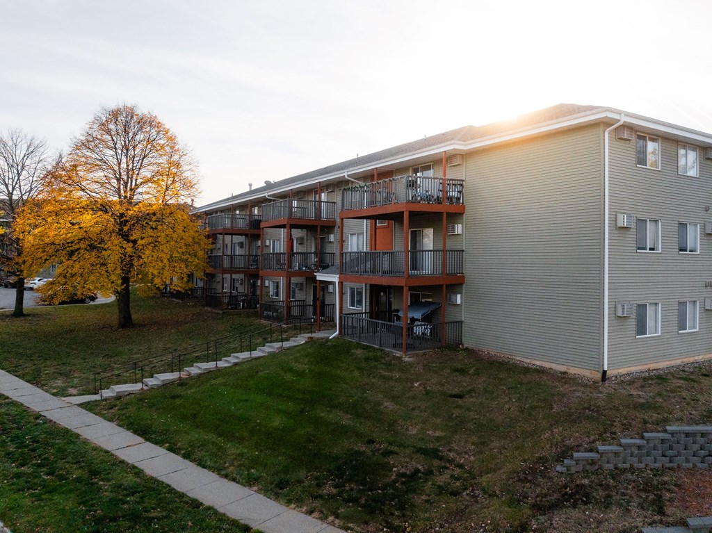 A building with a balcony and a tree with yellow leaves at Rosemont Place Apartments, Iowa, 50320