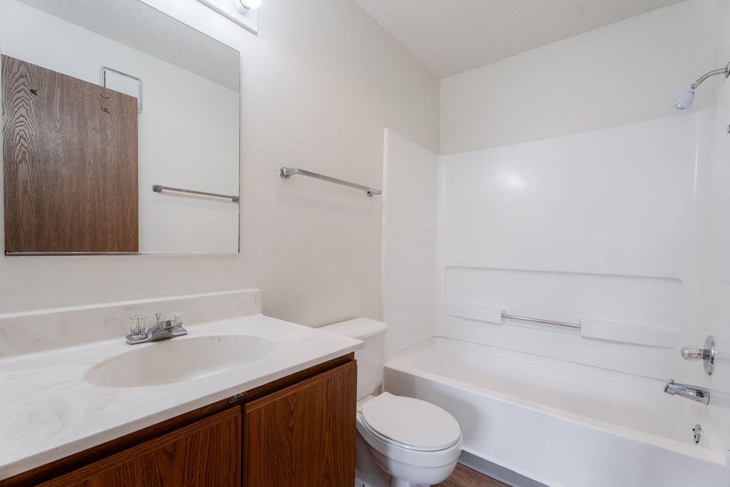 A white bathroom with a toilet, sink, and bathtub at Rosemont Place Apartments, Des Moines, Iowa