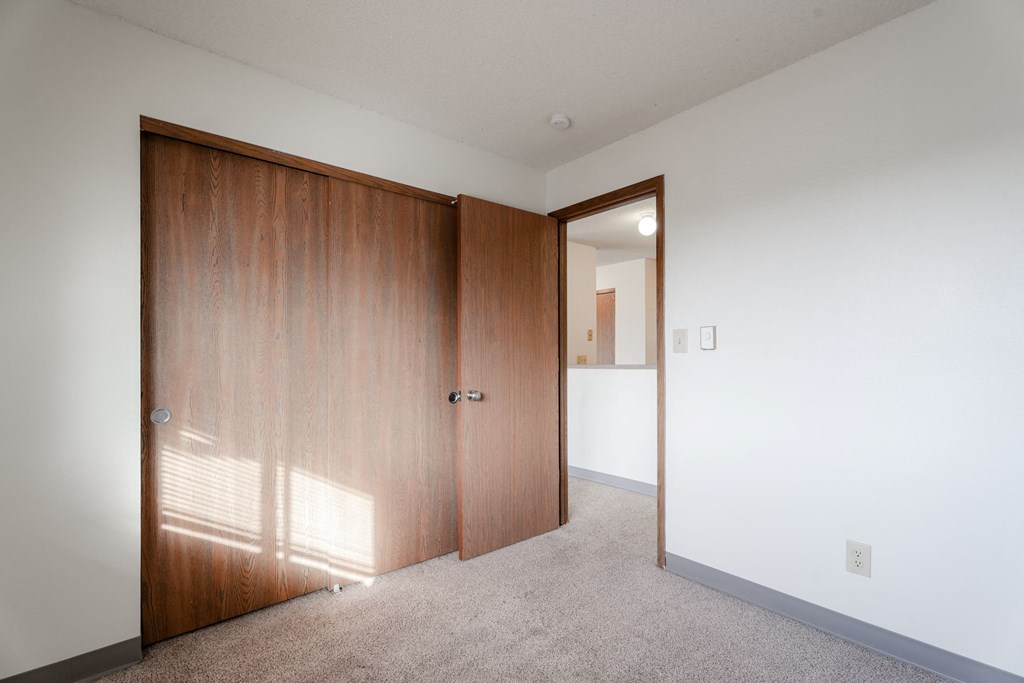 A room with a white wall and a brown door at Rosemont Place Apartments, Des Moines, IA