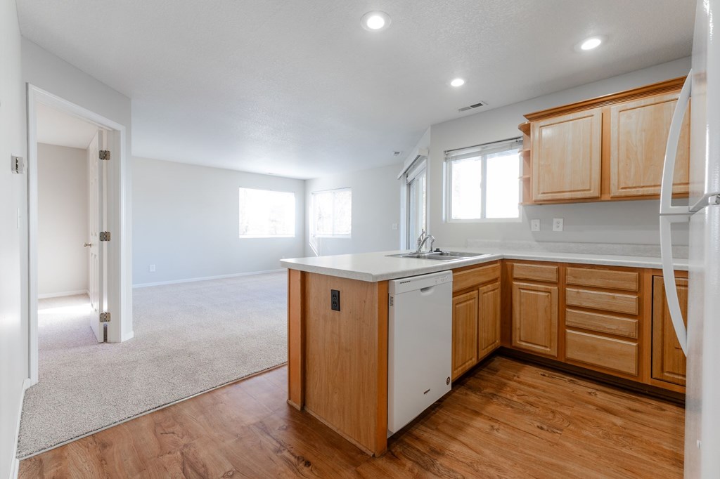 A kitchen with wooden cabinets and a white fridge. at Saylorville Lakeside, Polk City, Iowa