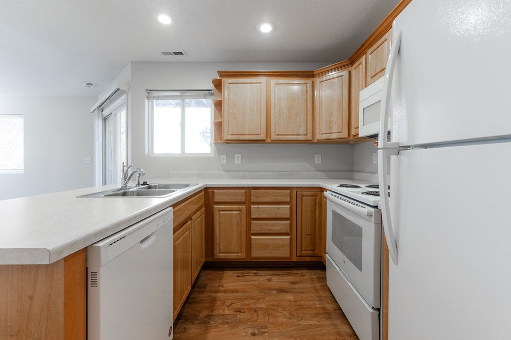 A kitchen with wooden cabinets and white appliances. at Saylorville Lakeside, Polk City, Iowa