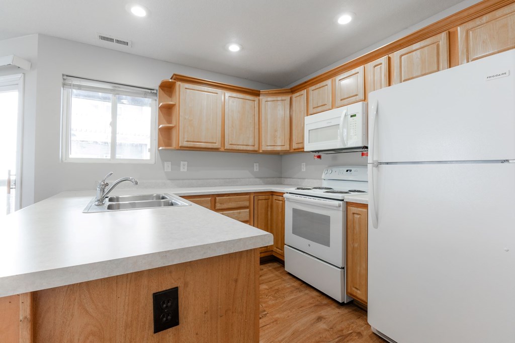 A kitchen with wooden cabinets and white appliances. at Saylorville Lakeside, Polk City, 50226