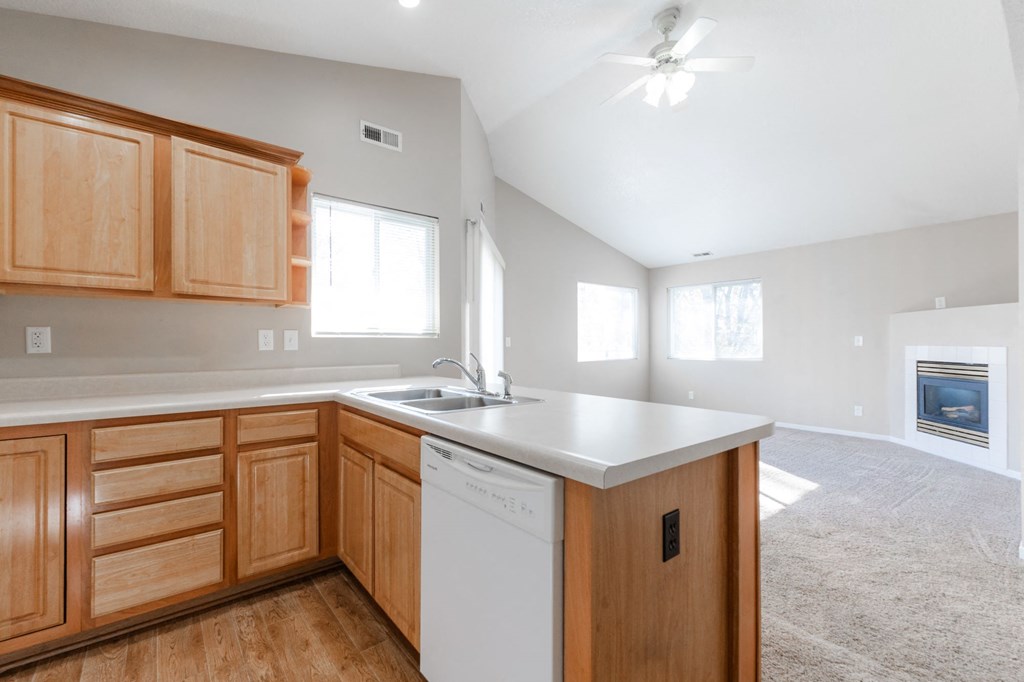 A kitchen with wooden cabinets and a white dishwasher. at Saylorville Lakeside, Polk City