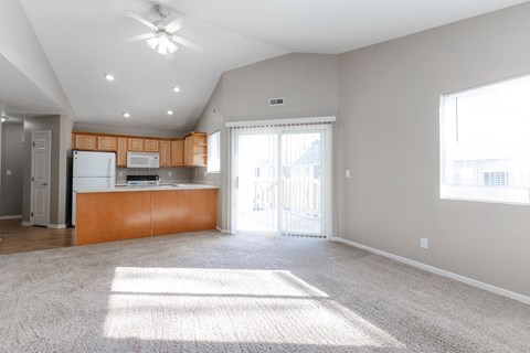 A spacious living room with a carpeted floor and a ceiling fan.