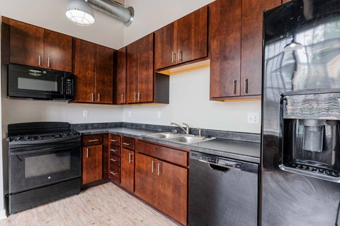 A kitchen with wooden cabinets and black appliances.