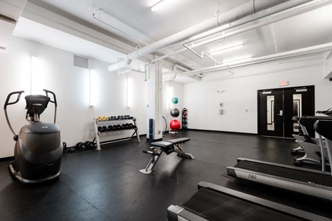 A gym with a treadmill, weights, and exercise equipment.
