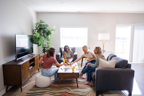 Four women are sitting on a couch in a living room.
