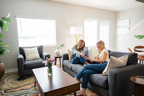 Two women sitting on a couch in a living room.