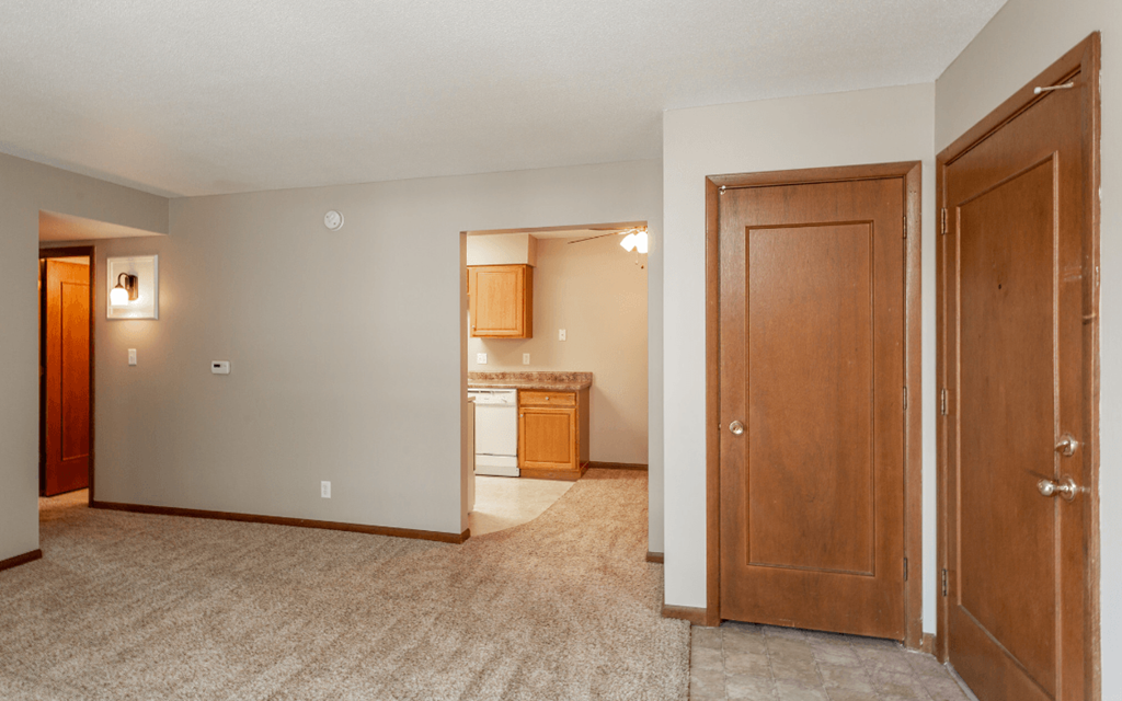 an empty living room and kitchen with a door open to a bedroom at Lake Shore Place Apartments, Ankeny, Iowa