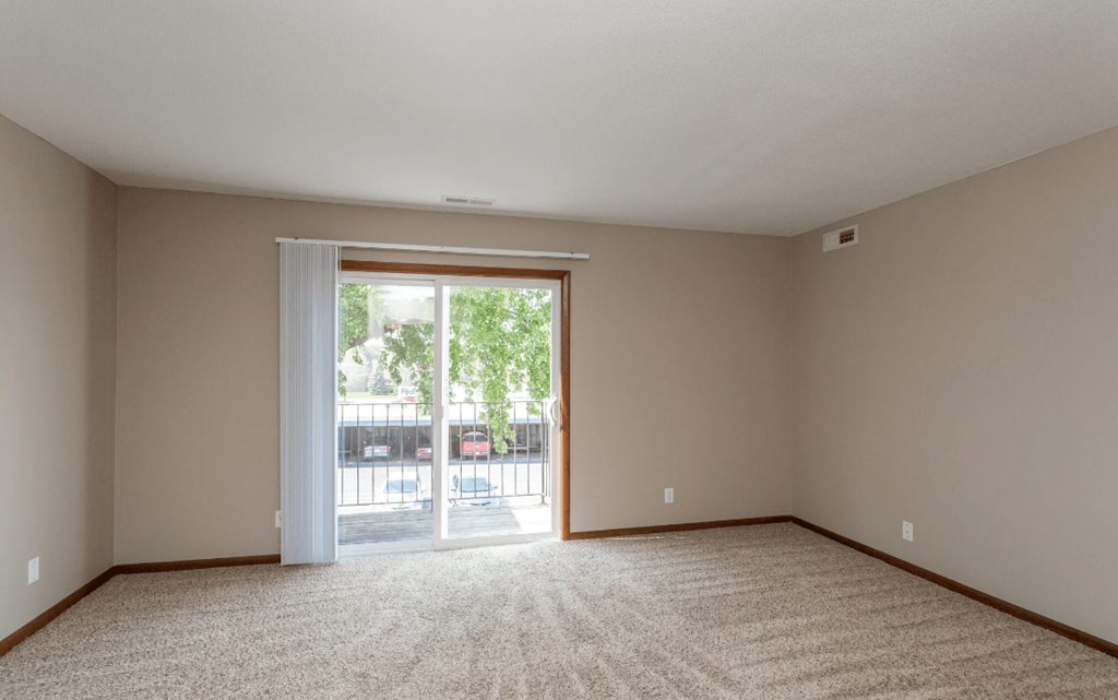an empty living room with sliding glass doors to a patio at Lake Shore Place Apartments, Ankeny