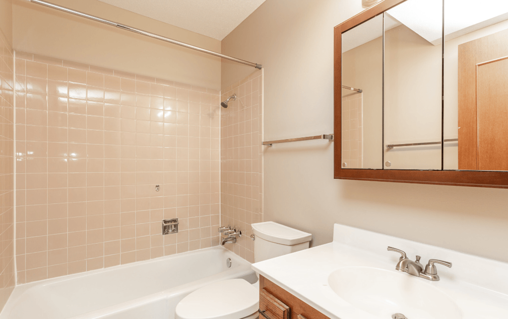 a bathroom with a tub sink and toilet and a mirror at Lake Shore Place Apartments, IA, 50021
