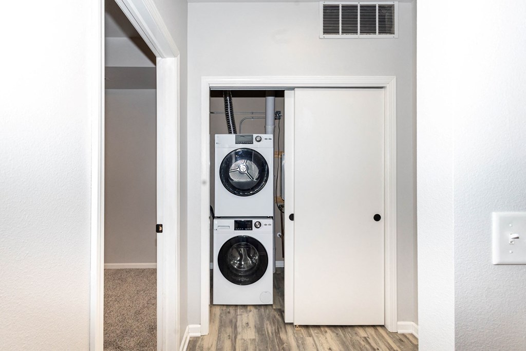 A white door is open to reveal a black washing machine and dryer at Meadowlark Place Apartments, Grimes, IA