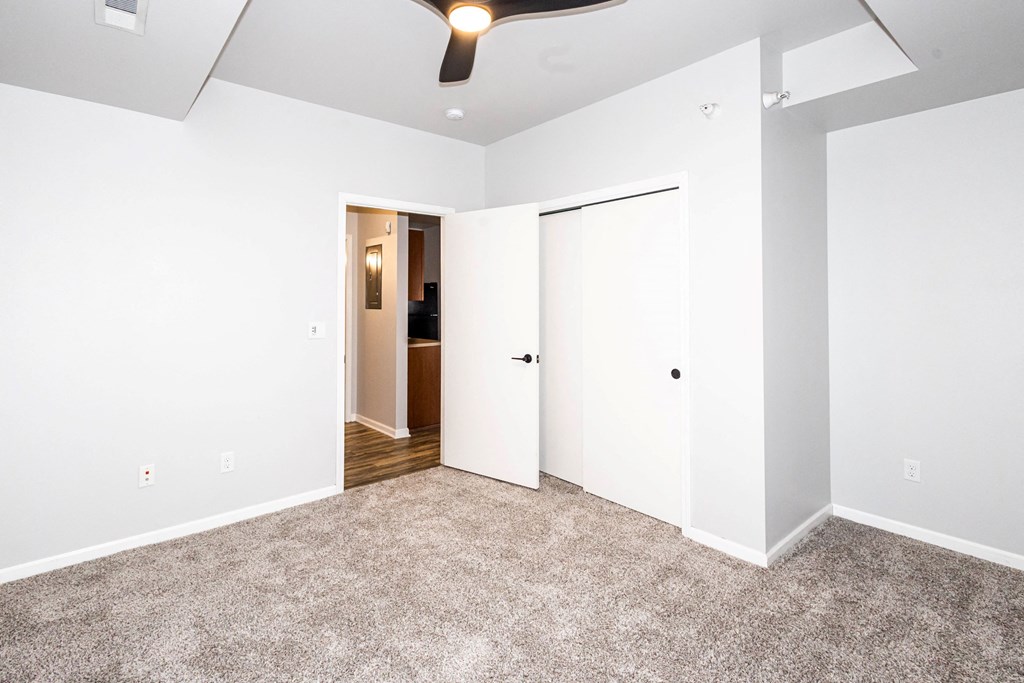 A room with a carpeted floor and a ceiling fan at Meadowlark Place Apartments, Grimes, IA