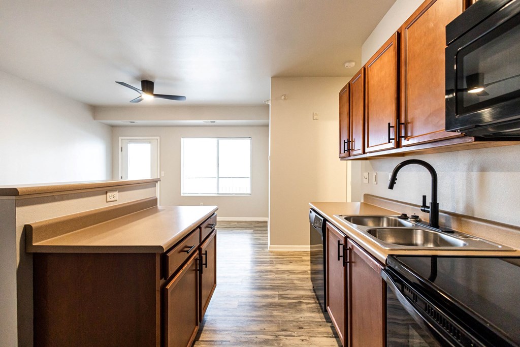 A kitchen with dark wood cabinets and a black stove top oven at Meadowlark Place Apartments, Iowa, 50111