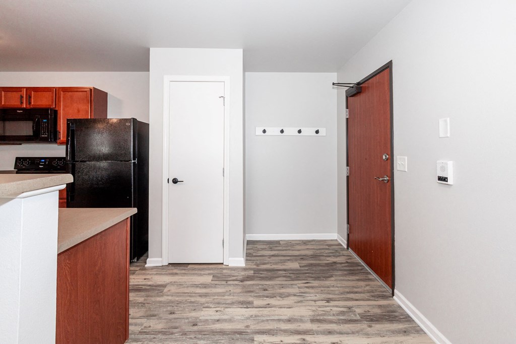 A kitchen with a black fridge and wooden cabinets at Meadowlark Place Apartments, Grimes, Iowa
