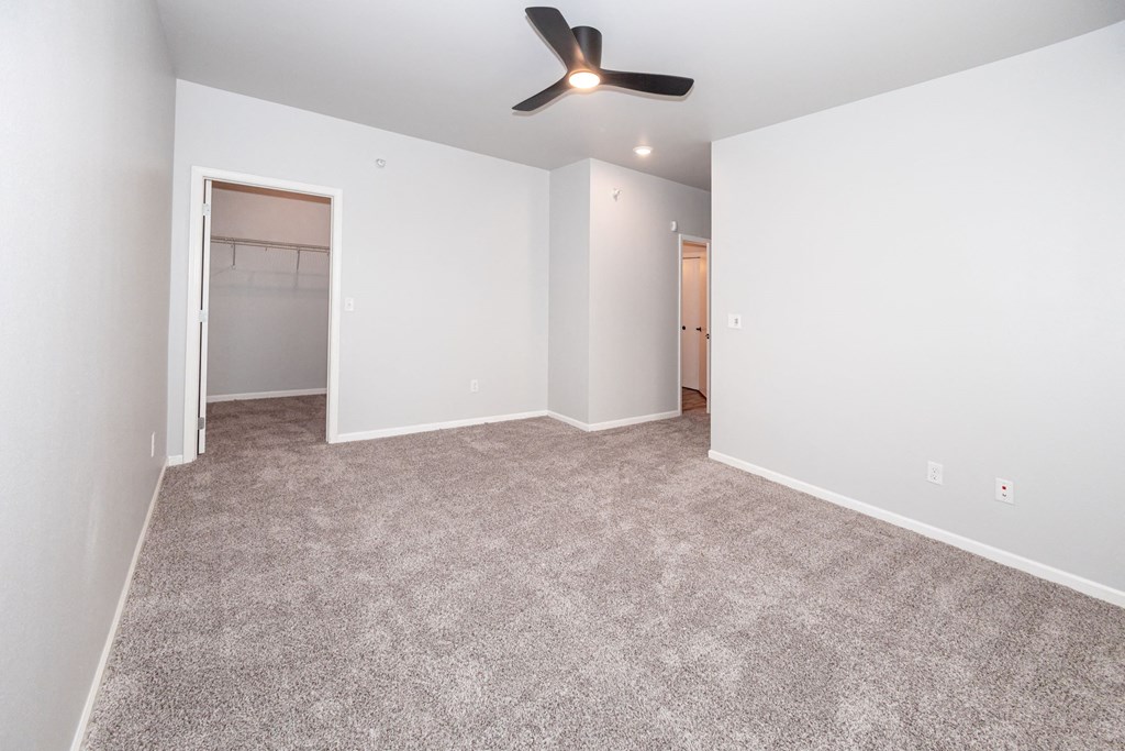 A room with a ceiling fan and carpeted floor at Meadowlark Place Apartments, Grimes, IA,  50111