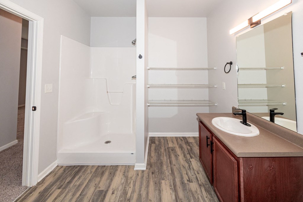 A bathroom with a white tub and wooden floors at Meadowlark Place Apartments, Grimes