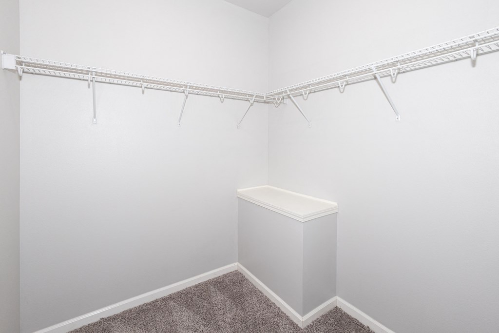 A white closet with a carpeted floor and a white bench at Meadowlark Place Apartments, Grimes, IA,  50111