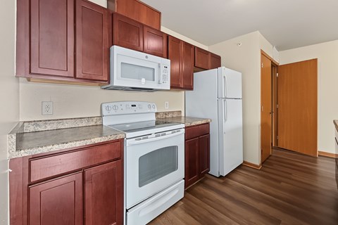 A kitchen with brown cabinets and white appliances.