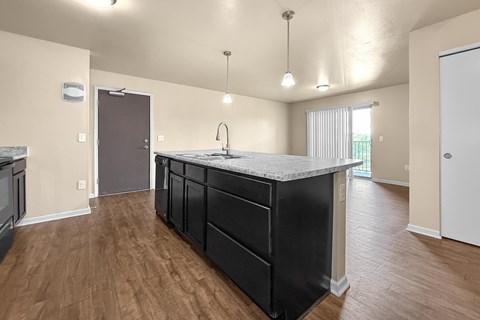 A kitchen with a black counter top and wooden floors.