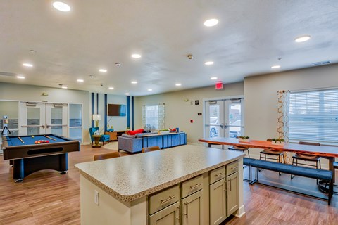 A room with a pool table, a bar, and a bench.