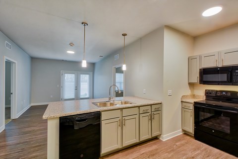A kitchen with a black oven and white cabinets.