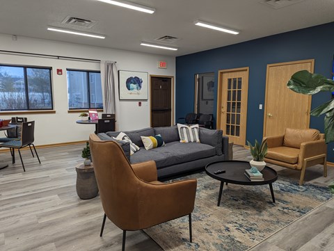 A living room with a grey couch, a brown chair, and a black coffee table.