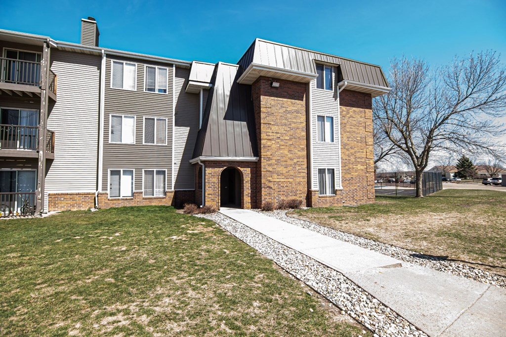 an apartment building with a sidewalk in front of it at Penbrooke Place Apartments, South Dakota