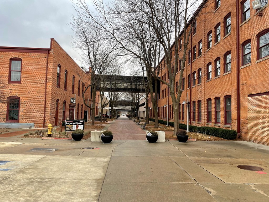 A long brick building with a walkway in front.at Plant 1 Lofts, N. Newton, IA  