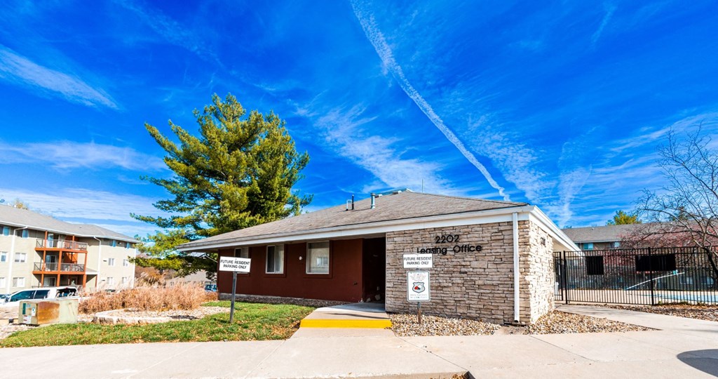 a small brick building with a fence and a tree in front of it at Rosemont Place Apartments, Des Moines, IA