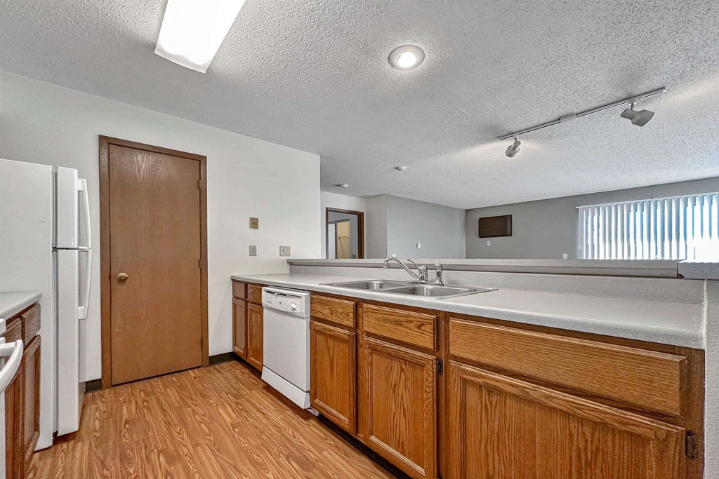 a kitchen with wooden cabinets and a sink and a refrigerator a kitchen with wooden cabinets and a sink and a refrigerator at Autumn Park, Sioux Falls South Dakota