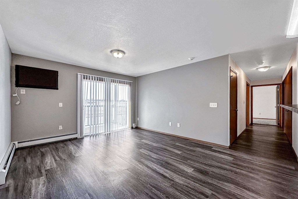 an empty living room with wood flooring and a sliding glass door an empty living room with wood flooring and a sliding glass door at Autumn Park, South Dakota