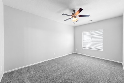 A room with a ceiling fan and a window with blinds.