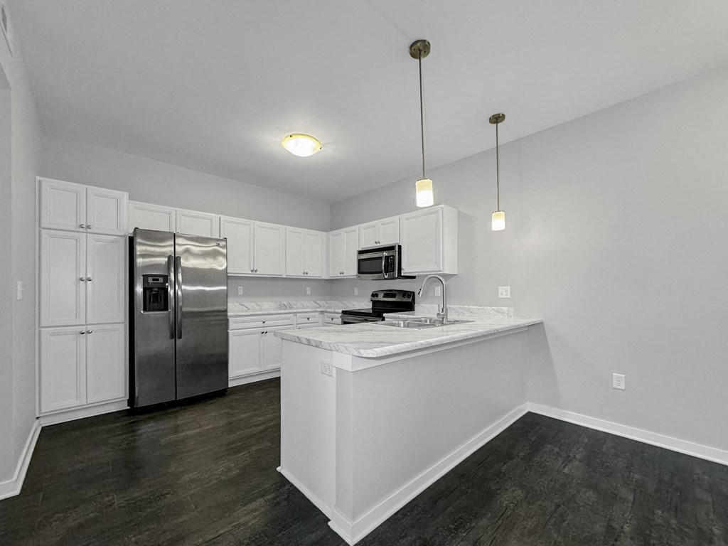 an empty kitchen with white cabinets and a stainless steel refrigerator at Stonegate Crossing Apartments, Clive, IA